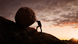 Man finding it challenging pushing a large boulder up a hill