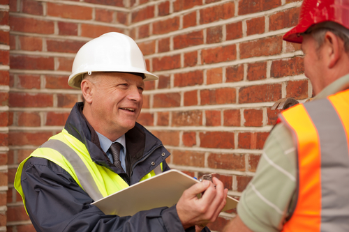 Site Manager with clipboard talking to construction worker