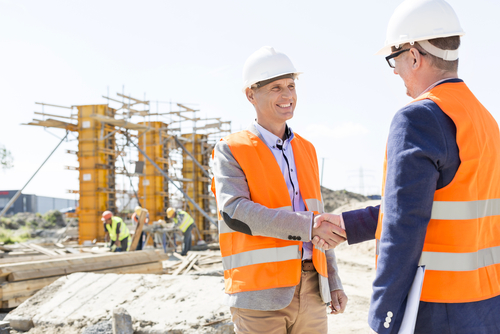 Subcontractors representative shaking hands in front of a construction site